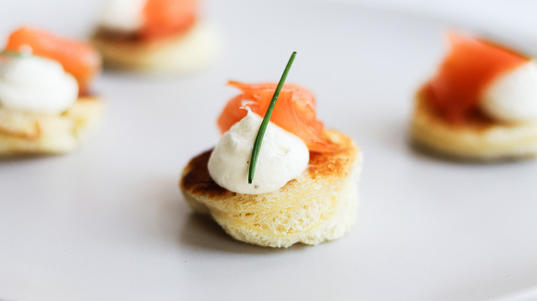 Smoked salmon brioche bite canape topped with cream and fresh chive