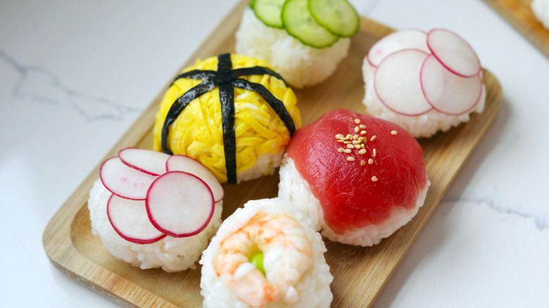 Six decorative sushi balls on wooden serving board