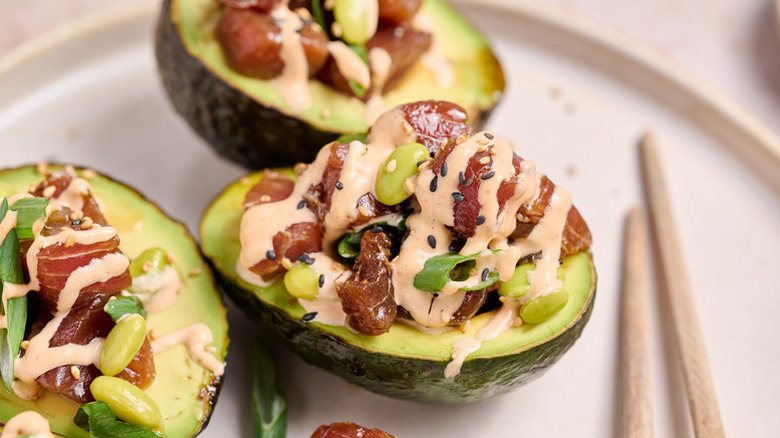 Tuna poke-stuffed avocado halves, drizzled with sriracha mayo