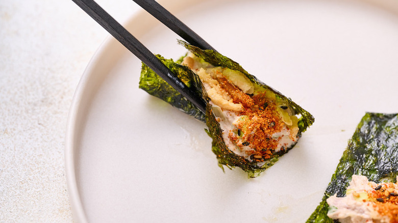 Tuna salad nori wrap picked up from plate with chopsticks