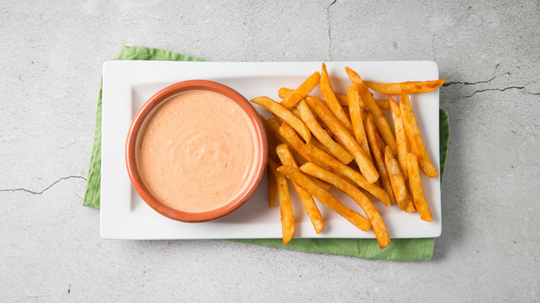 Bowl of chipotle mayo on plate with pile of fries