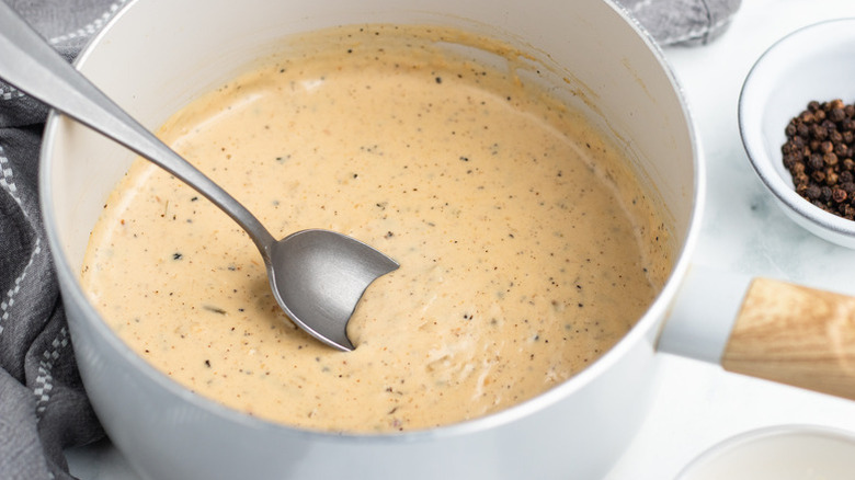 Saucepan of peppercorn sauce with spoon resting in it
