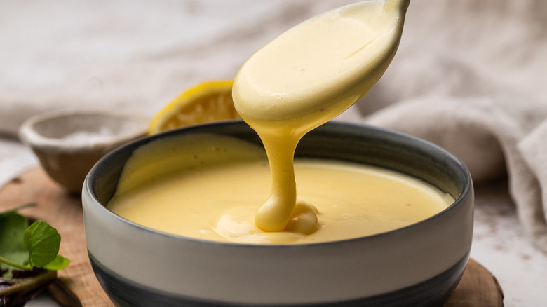 Spooning hollandaise sauce from bowl