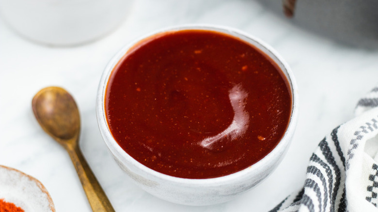Bowl of BBQ sauce next to mini gold spoon