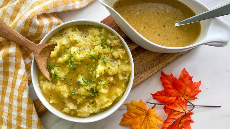 Gravy in gravy boat and poured over bowl of mashed potatoes