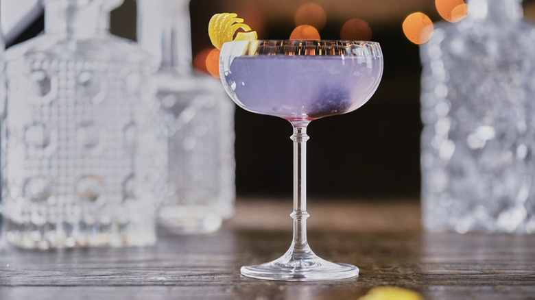 Pale purple cocktail in long-stemmed glass, garnished with lemon peel