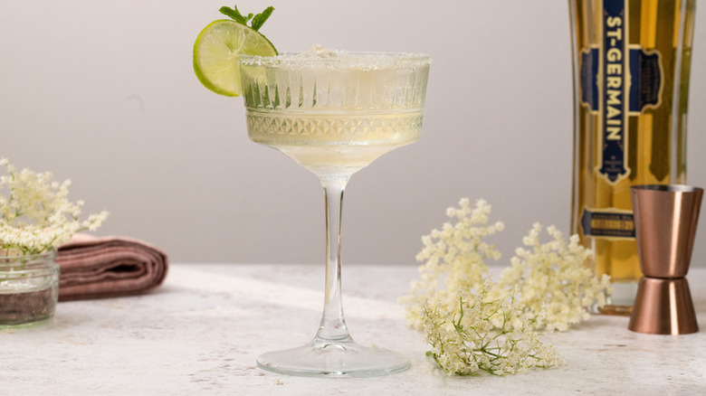 Elderflower cocktail in long-stemmed glass, garnished with a lime slice