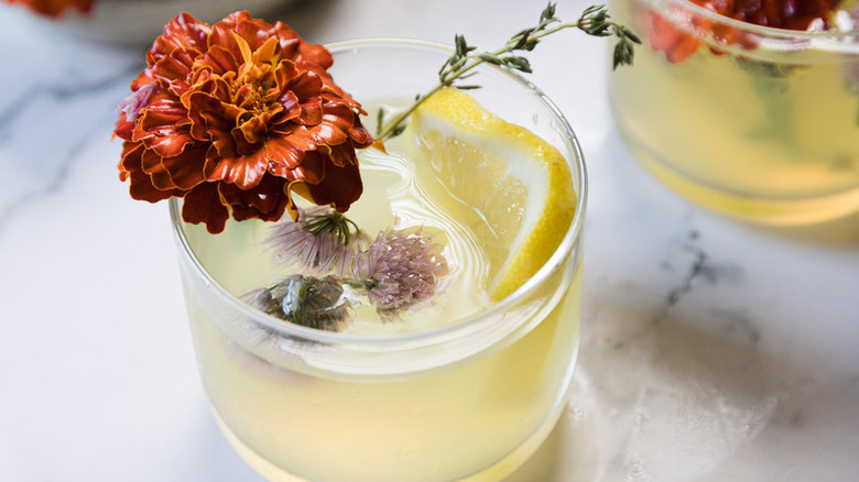 Limoncello cocktail in glass, garnished with lemon slice and edible flowers