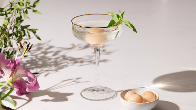 Lychee martini cocktail garnished with sprig of fresh Thai basil