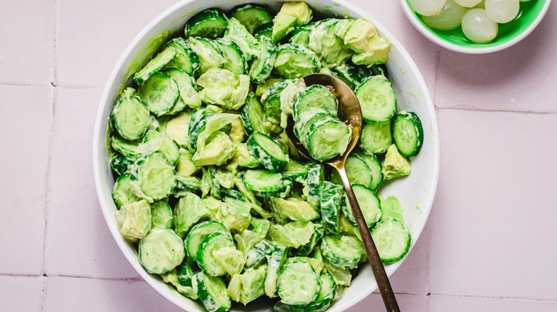 Creamy cucumber salad in bowl with spoon