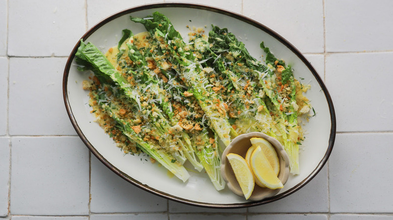 Caesar salad lettuce spears on serving plate with lemon wedges