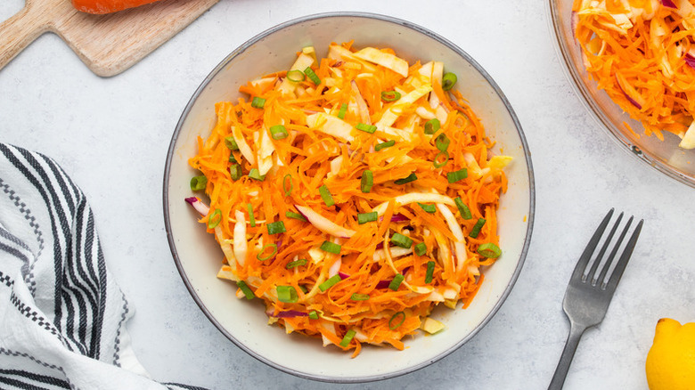 Bowl of carrot and cabbage slaw, garnished with chopped green onions