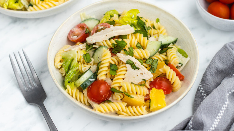 Bowl of chicken pasta salad with cherry tomatoes and cucumber