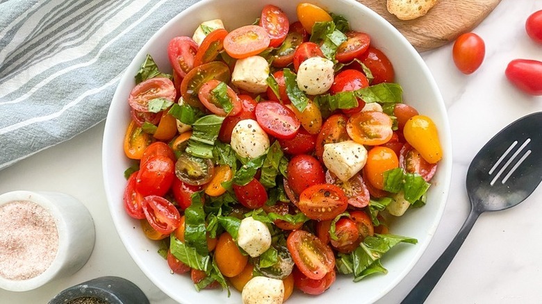 Bowl of chopped Caprese salad with grape tomatoes, mozzarella, and basil
