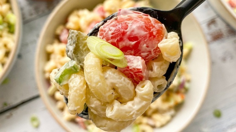 Spooning creamy macaroni salad from bowl