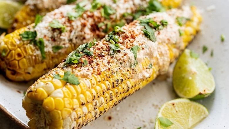Grilled Mexican street corn on plate with lime wedges