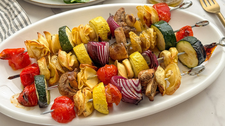 Grilled vegetable and tortellini skewers on white plate