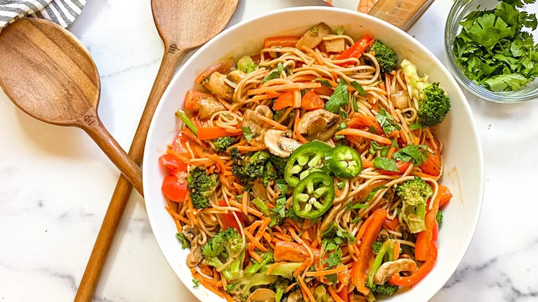 Spicy Peanut Soba Noodle Bowl in white bowl next to wooden utensils