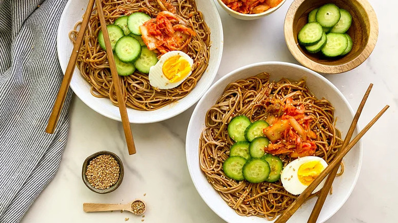 Bibim Guksu (Korean Cold Noodles) in two white bowls with chopsticks