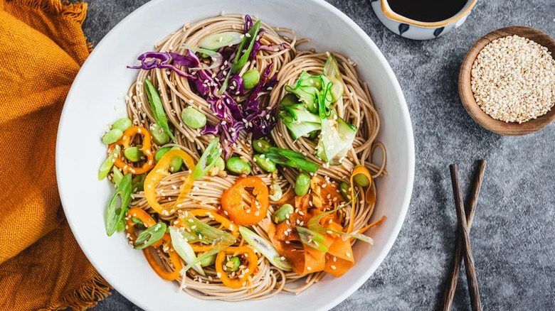 Buckwheat Soba Noodle Veggie Bowl on grey surface with bowl of sesame seeds
