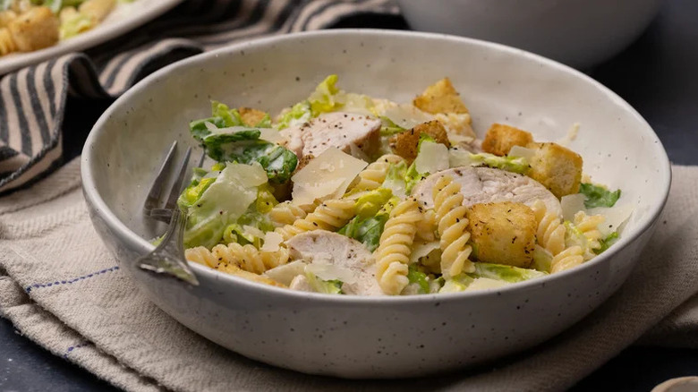 Caesar Chicken Pasta Salad in large white bowl with fork