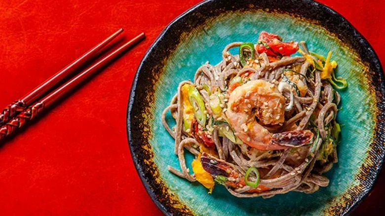 Cold Soba Noodle Salad with Shrimp, Mango, and Tomato on blue plate on red background