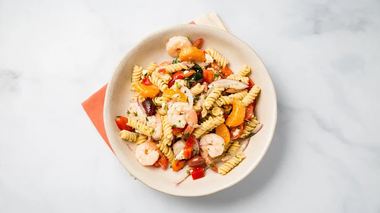 Greek Shrimp Pasta Salad in beige bowl on white countertop