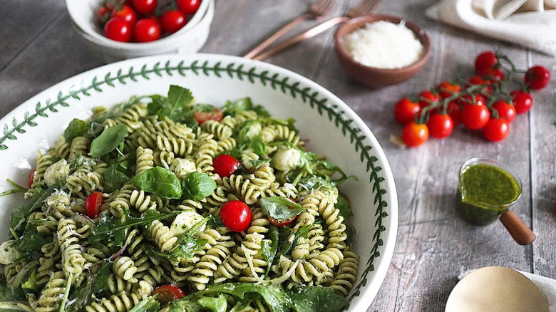 Summer Pesto Pasta Salad in white and green bowl with tomatoes