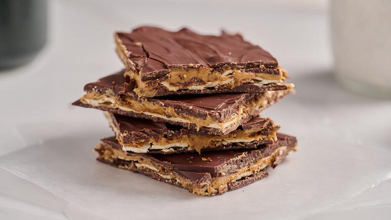 Stack of peanut butter pretzel bark on pieces of white parchment paper