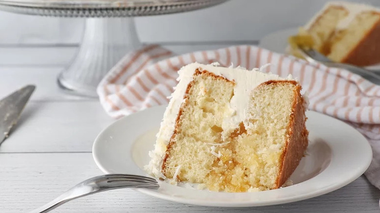 Slice of Best Pineapple Coconut Cake on white plate work fork