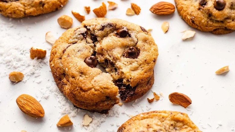 Chewy Coconut Almond Chocolate Chip Cookie broken in half on white surface