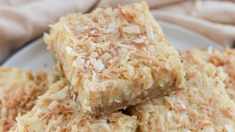 Chewy Sweet Coconut Bars stacked on white plate