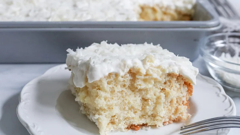 Slice of Pineapple Coconut Poke Cake on white plate