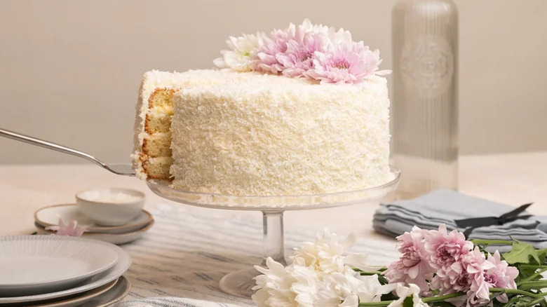 Super Coconut Layer Cake with purple flowers on cake stand