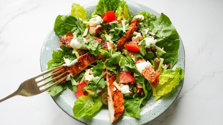 Bowl of Cajun chicken salad with lettuce and herbs