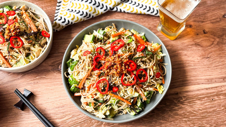 Bowl of chicken soba salad topped with sliced red chiles