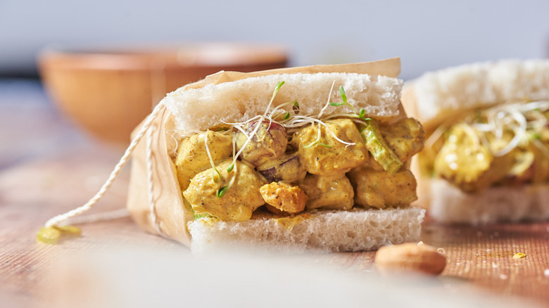 Curried chicken salad sandwich wrapped in brown paper