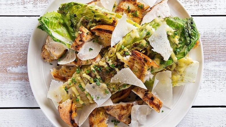 Grilled chicken Caesar salad on a plate with shaved Parmesan