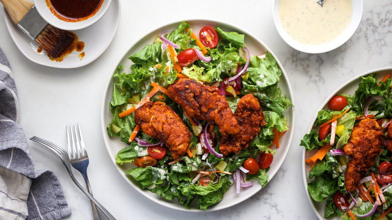 Plates of salad topped with crispy hot chicken