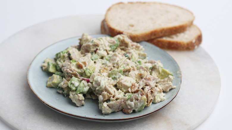 Creamy chicken salad on a plate next to slices of bread