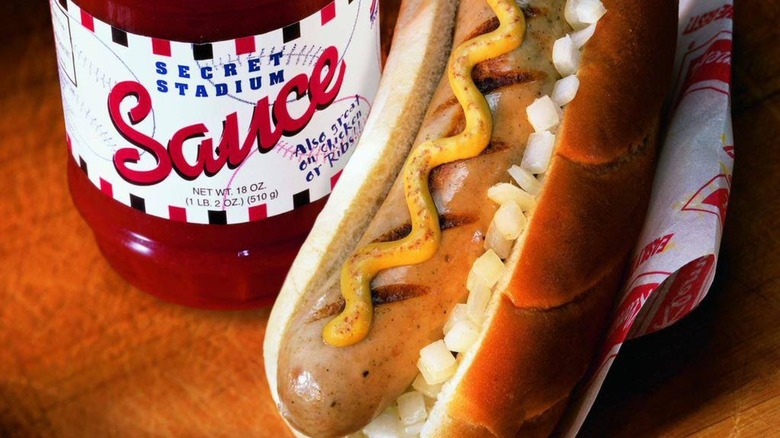 Bratwurst with onions and mustard with bottle of Secret Stadium Sauce