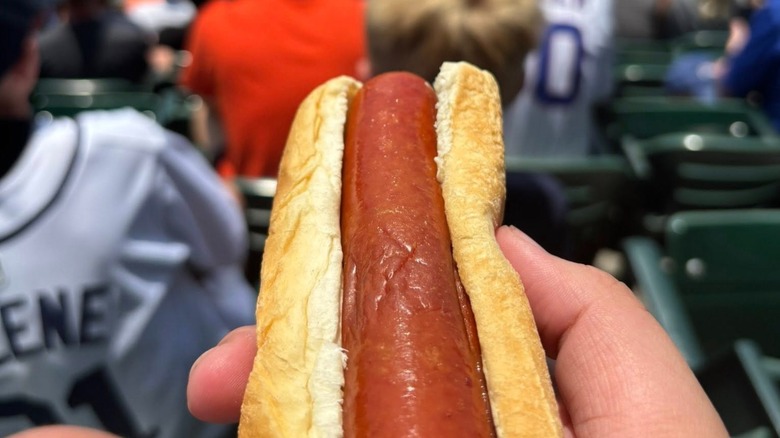 Hand holding hot dog in front of blurred seats