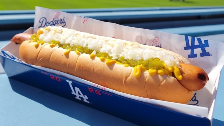 Dodger dog outside in blue tray with onions, relish, and mustard