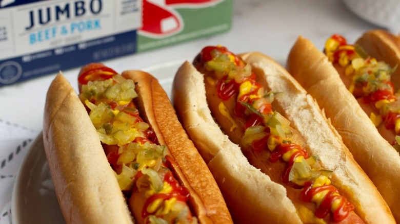 Three hot dogs with Kayem package blurred in background