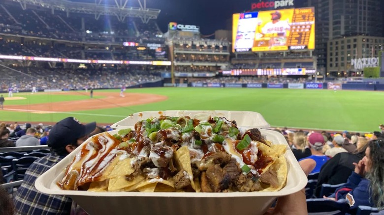 Tri-tip nachos in container with blurred field in background