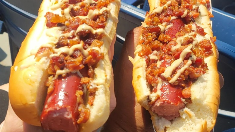 Two hot dogs with bacon and drizzle of sauces