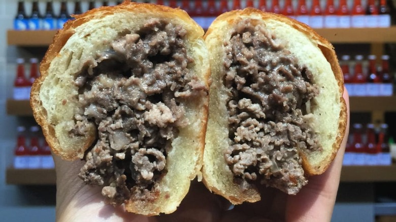 Hands holding halves of Philly cheesesteak