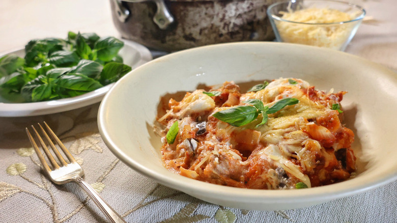 Gnocchi lasagne bake served in bowl with basil garnish with cheese and more basil in the back