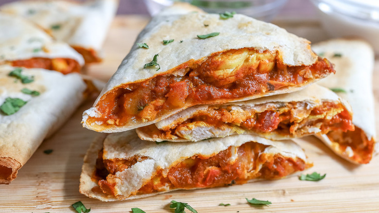 Stack of chicken tikka masala quesadillas sprinkled with fresh chopped herbs
