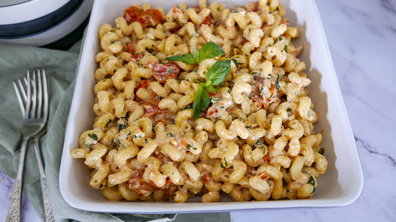 Feta and tomato pasta in baking dish, garnished with basil